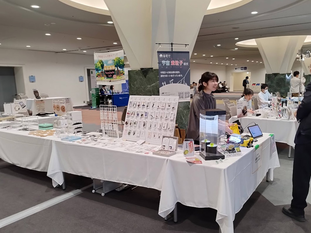 JpGU2025の加速キッチンブースで、検出器と手づくりグッズを並べた展示テーブル