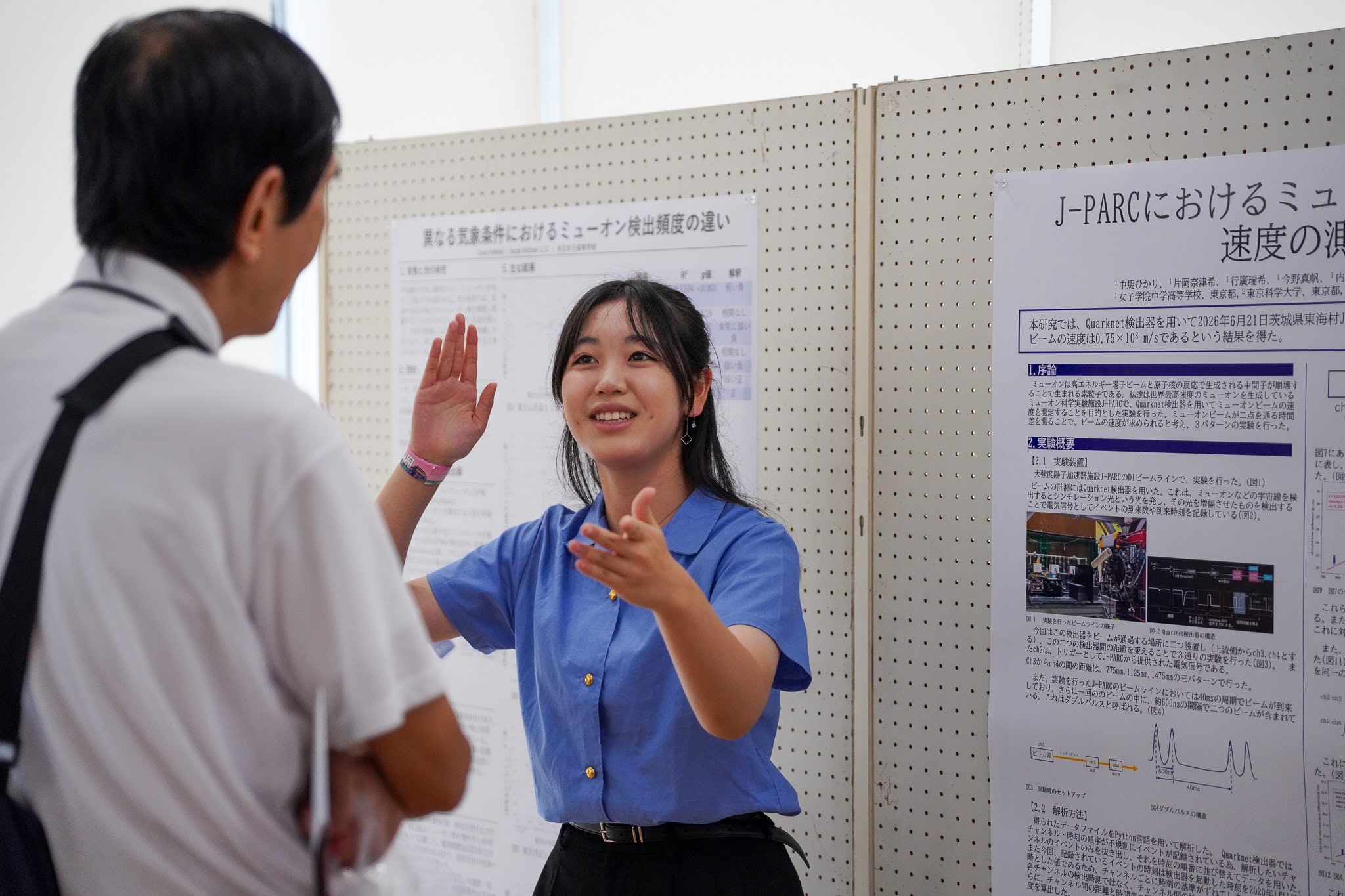 ポスター会場で、J-PARC でのミューオン実験の研究を来場者に説明する高校生