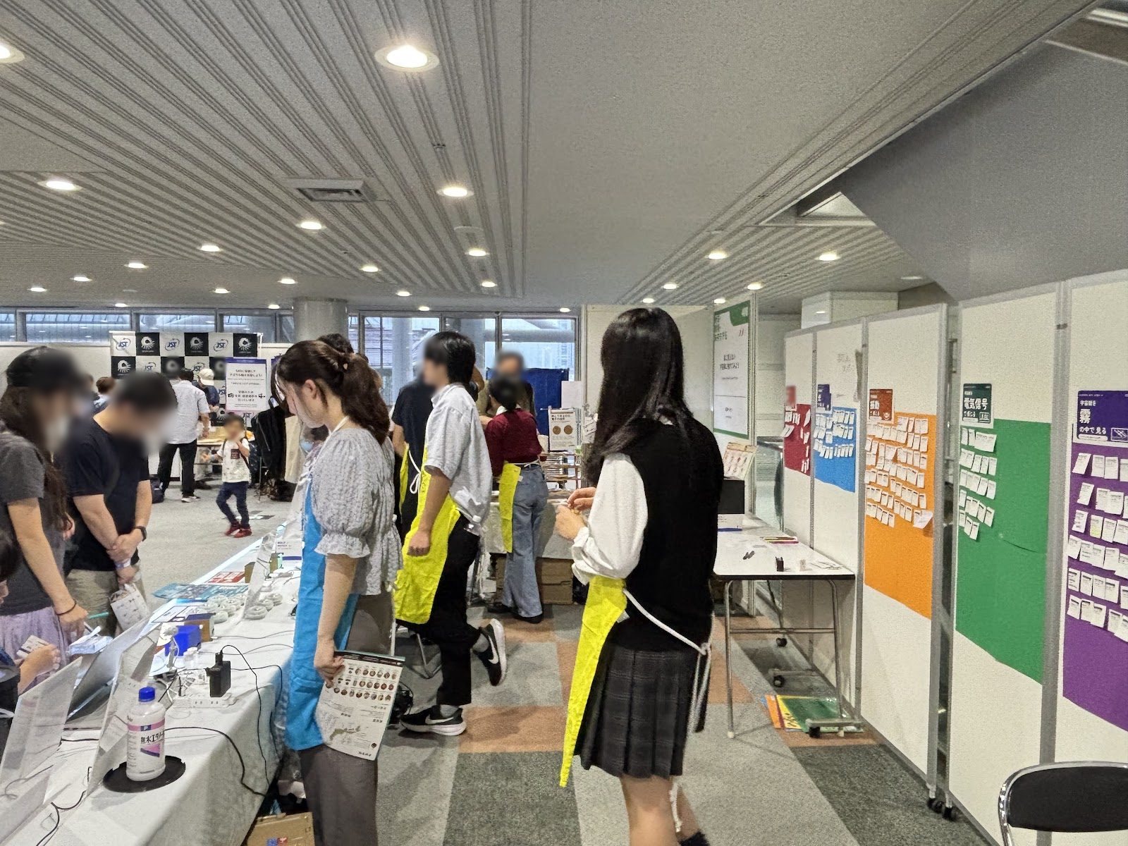 Visitors lined up in front of the booth while explainers in aprons help them