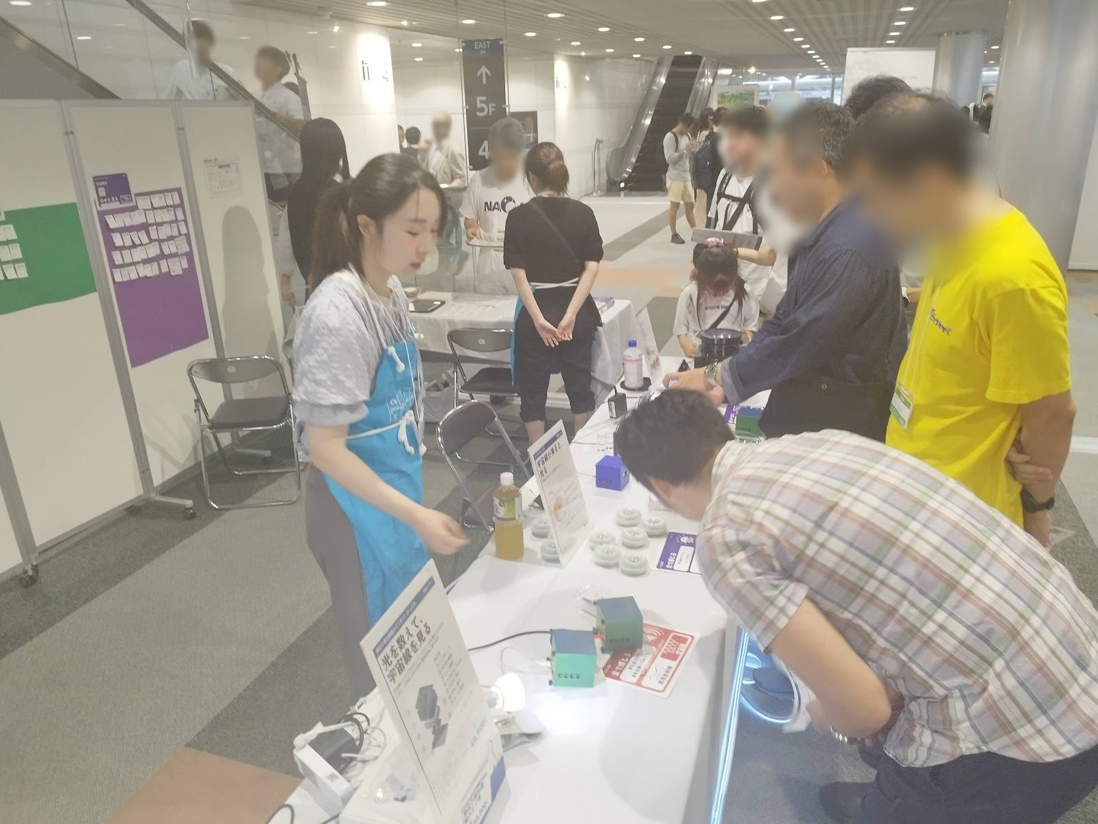 An explainer demonstrating a device to an adult visitor
