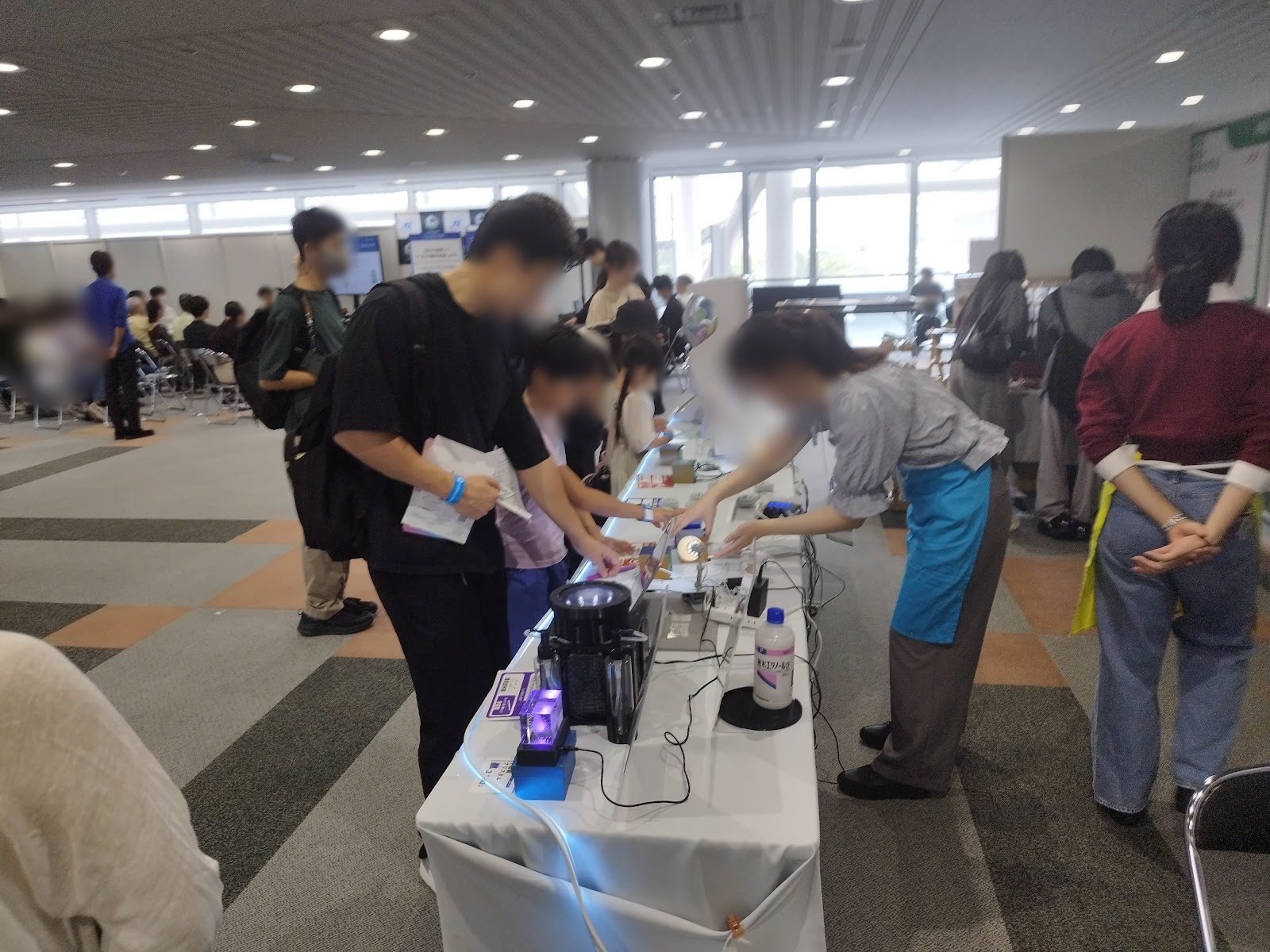 An explainer showing a device to a visitor at the booth