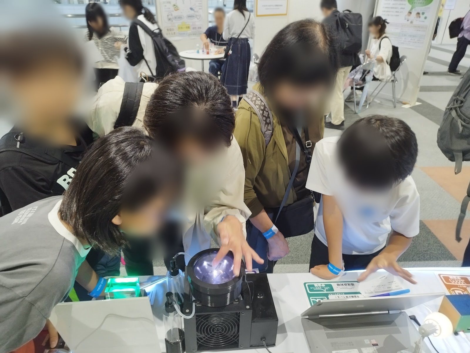 Children and adults peering into the light of the cloud chamber