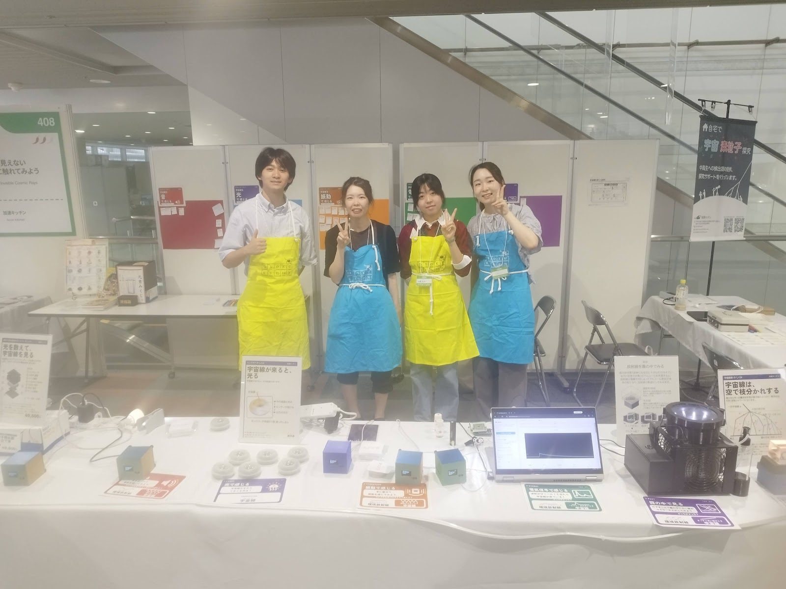 Four explainers in aprons making peace signs in front of the devices