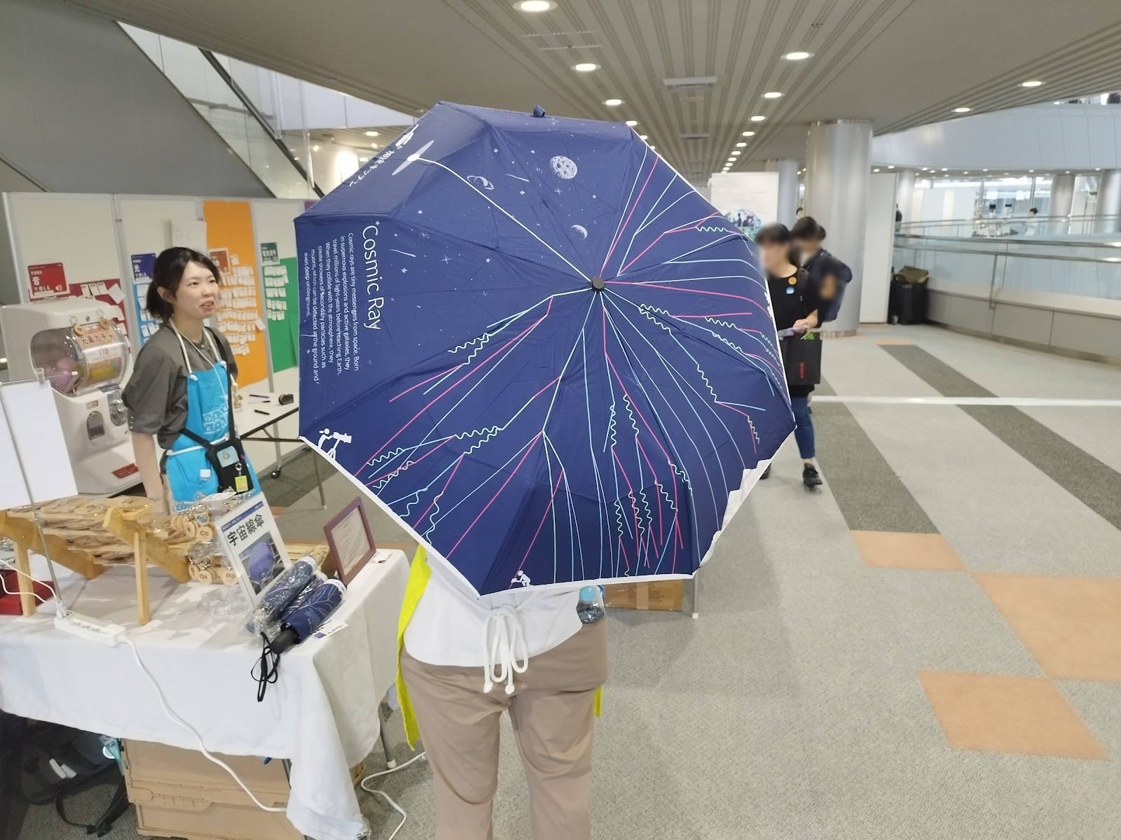 A navy umbrella printed with a cosmic-ray shower, held open