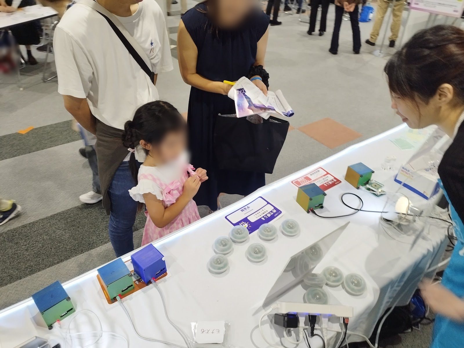 A parent and child looking at a row of small glowing detectors nicknamed mini-jellyfish
