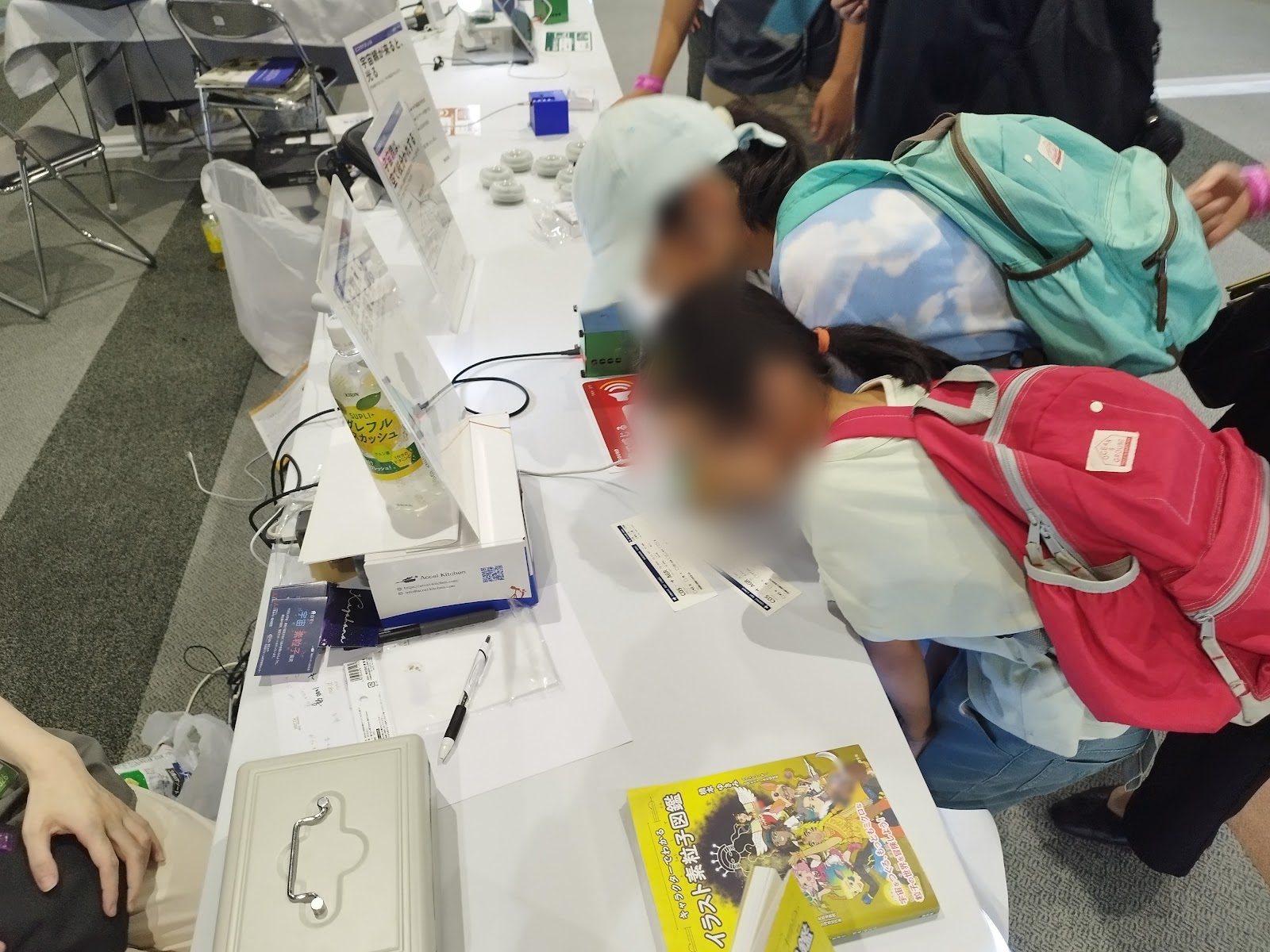 Children leaning close to a small detector on the table to listen to it