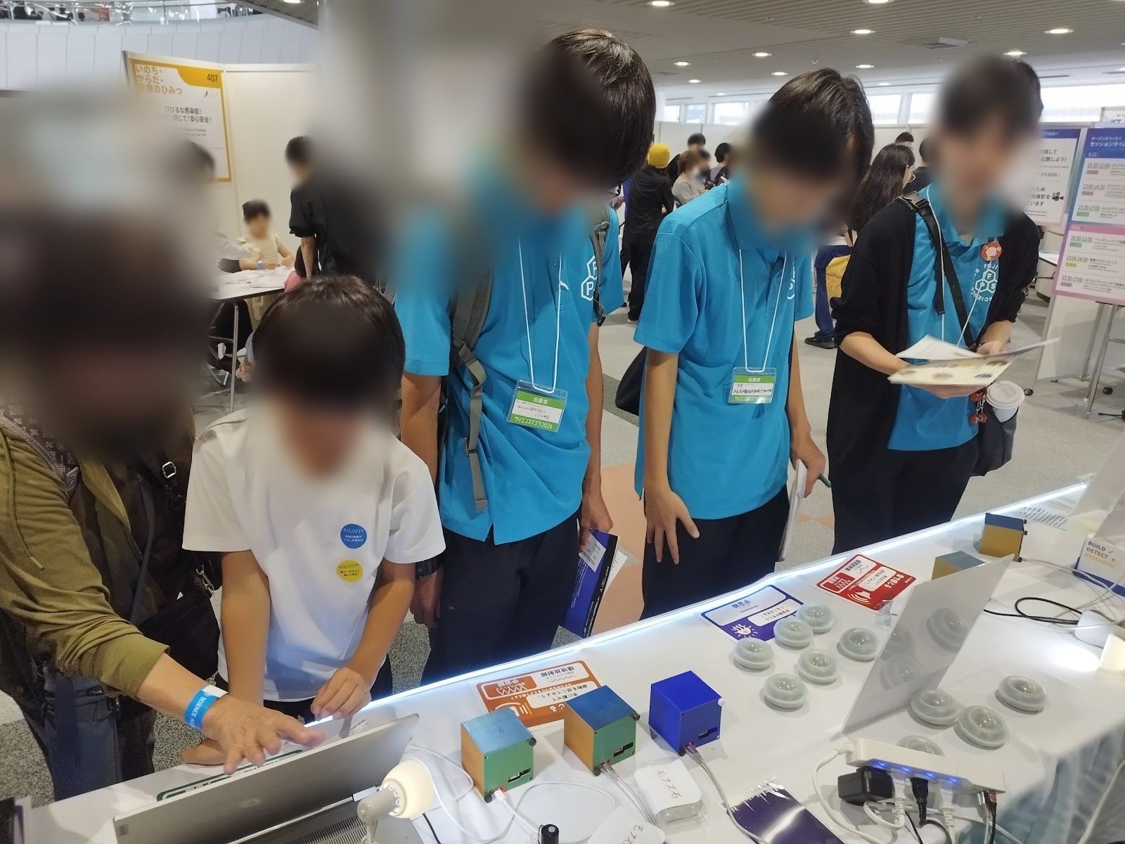 Students in light blue shirts peering at a detector screen