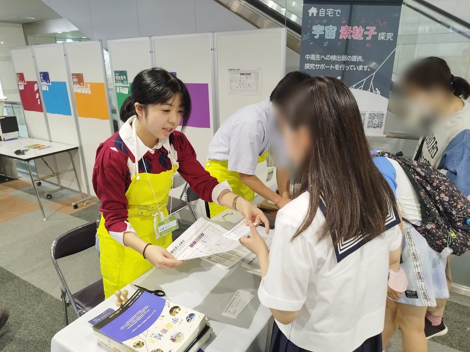 A school student in an apron handing a pass to a visitor